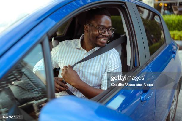 un conducteur afro-américain joyeux met sa ceinture de sécurité dans sa voiture - conduite responsable photos et images de collection