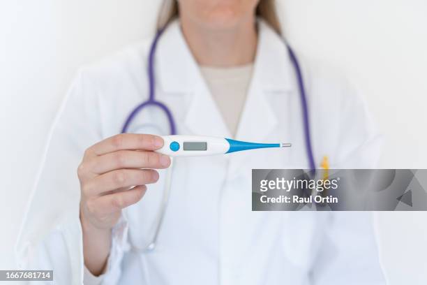 unrecognizable female doctor holding thermometer in clinic. - hot nurse stock-fotos und bilder