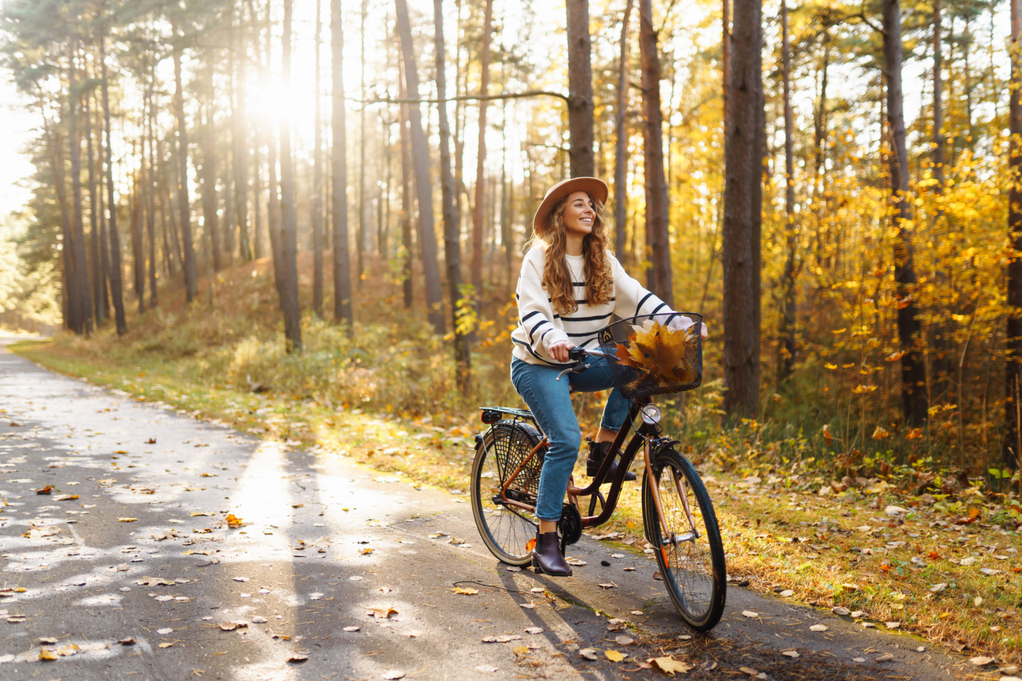 Happy active woman in stylish clothes rides a bicycle in an autumn park at sunset Happy active woman in stylish clothes rides a bicycle in an autumn park at sunset