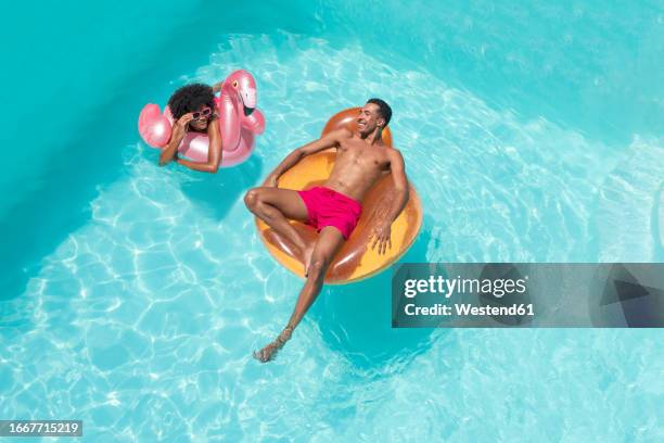 happy man and woman with inflatable float relaxing in pool - floating on water stock pictures, royalty-free photos & images