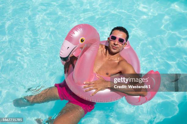 smiling man swimming with inflatable ring in pool - magenta stock pictures, royalty-free photos & images