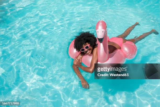 smiling young woman swimming with inflatable ring - swimming pool stock pictures, royalty-free photos & images