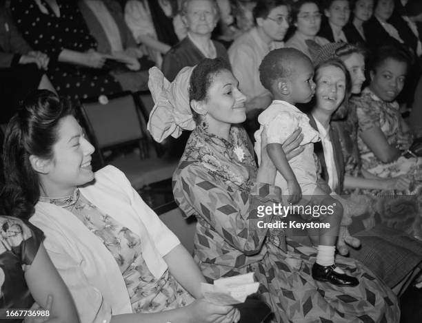 Woman and her small child are among an audience attending the Jubilee Celebration of the Women's Co-operative Guild at the Albert Hall in London,...