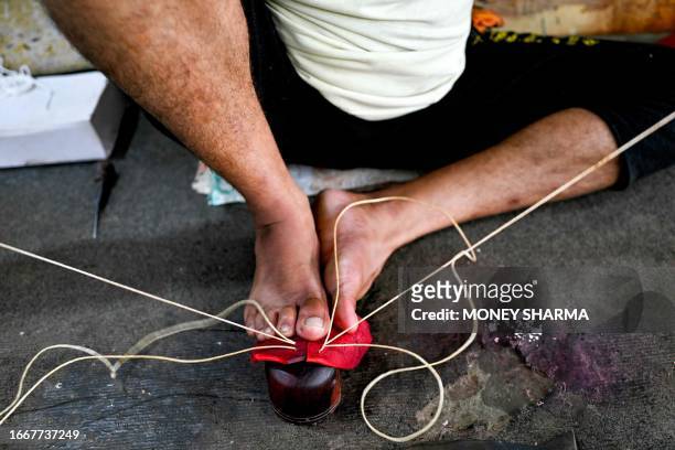 In this photograph taken on September 14 a worker sews leather seam of a cricket ball at a workshop in Meerut in India's northern state of Uttar...