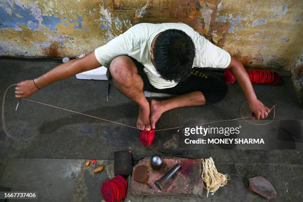 In this photograph taken on September 14 a worker sews leather seam of a cricket ball at a workshop in Meerut in India's northern state of Uttar...