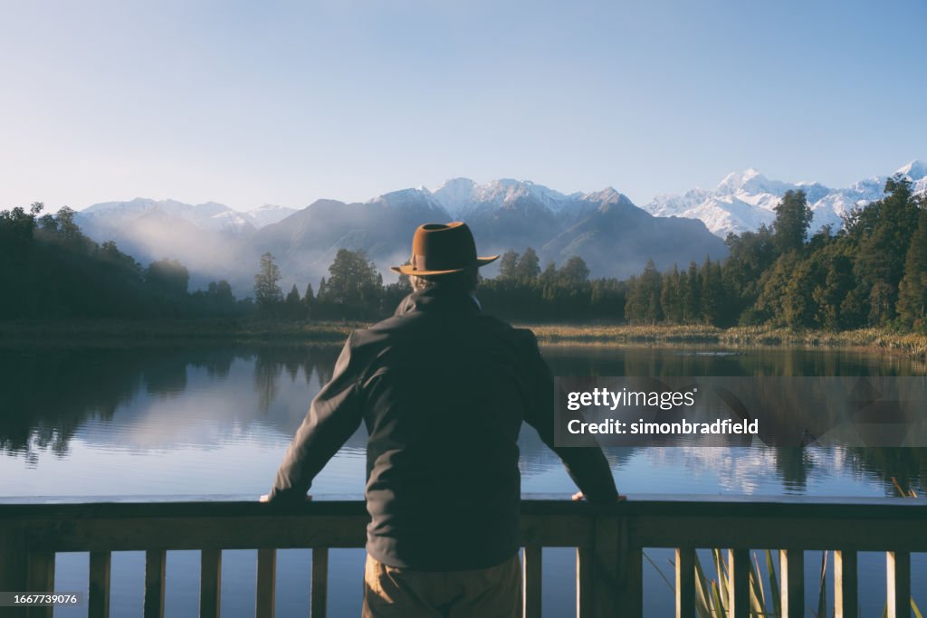 Fedora Wearing Man Travels To Lake Matheson, New Zealand