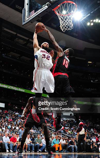 Amir Johnson of the Toronto Raptors blocks a dunk against Mike Scott of the Atlanta Hawks on April 16, 2013 at Philips Arena in Atlanta, Georgia....