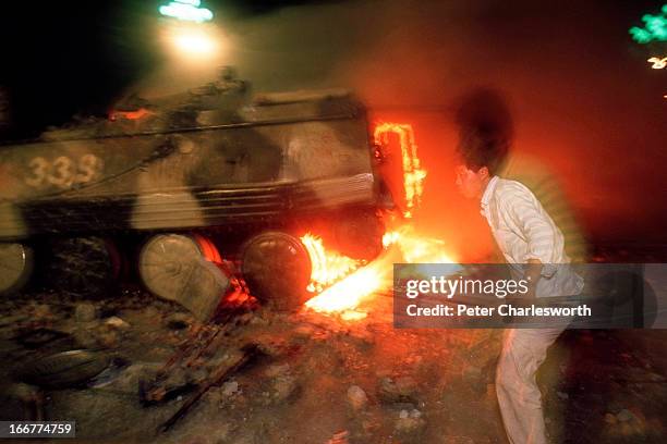Pro-democracy demonstrator attacks a burning armoured personnel carrier during the fighting that raged on Chang'an Avenue as soldiers marched and...