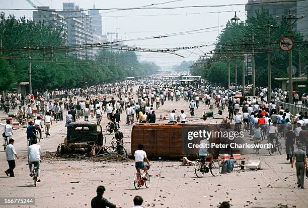 At the end of the pro-democracy protests in China, onlookers examine Chinese Army trucks and vehicles that were damaged or destroyed during the night...