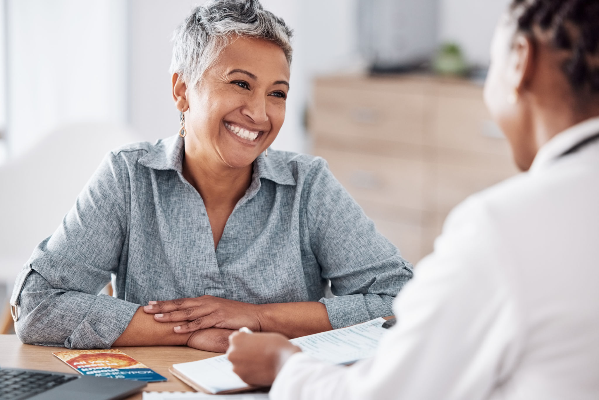 Paperwork, doctor or consulting a happy patient in meeting talking in hospital for history or healthcare record. Smile, medical or nurse with mature woman speaking of test results, update or document Paperwork, doctor or consulting a happy patient in meeting talking in hospital for history or healthcare record. Smile, medical or nurse with mature woman speaking of test results, update or document