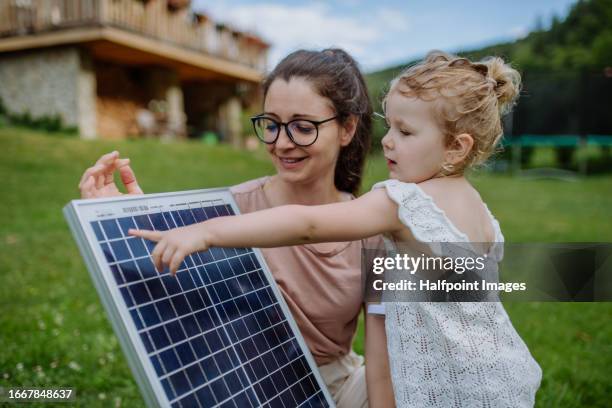 mother and daughter are looking at a solar panel up close. - clean energy bill stock pictures, royalty-free photos & images