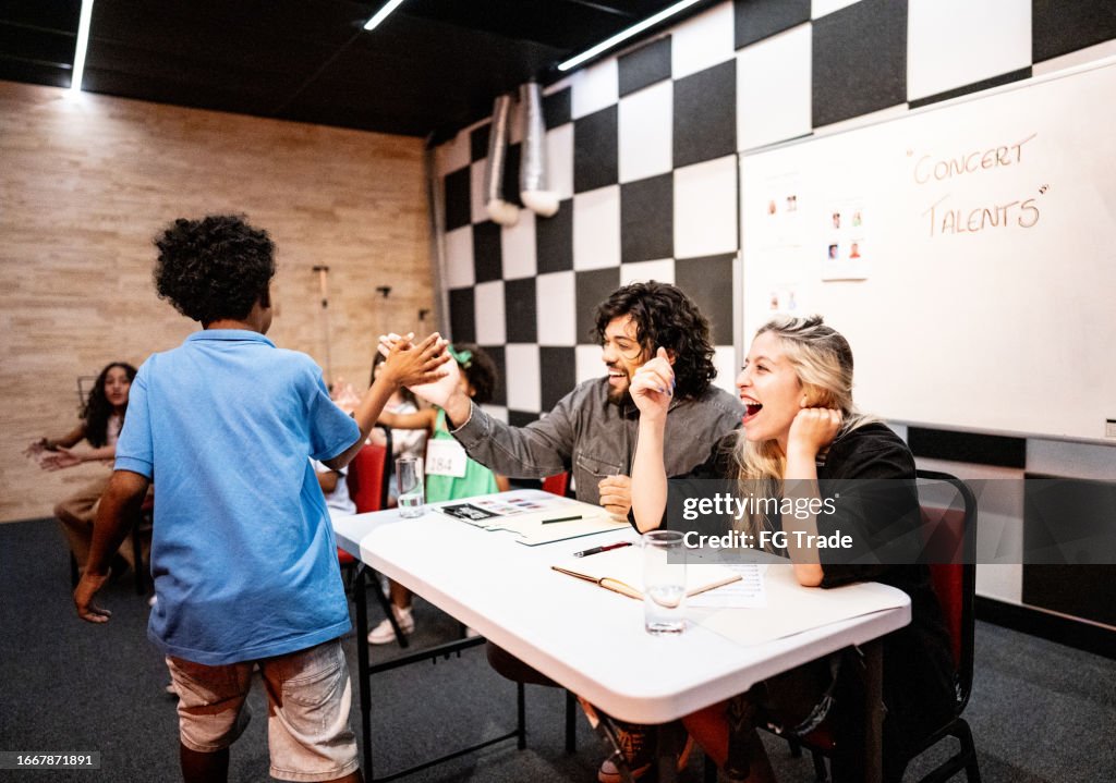 Boy doing a high five with judge in a music contest