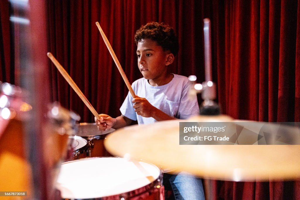 Niño tocando la batería en una escuela de música