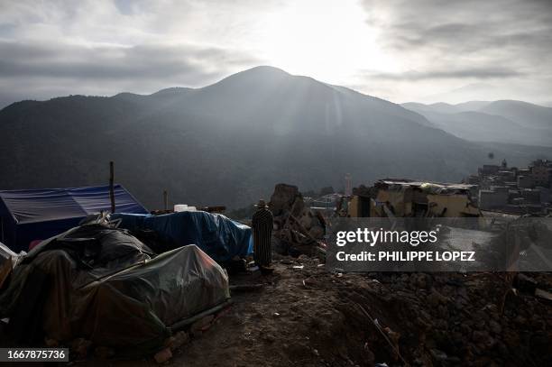 An earthquake survivor walks near tents used as makeshift shelters, as the sun rises over the Atlas mountains in the village of Moulay Brahim in the...