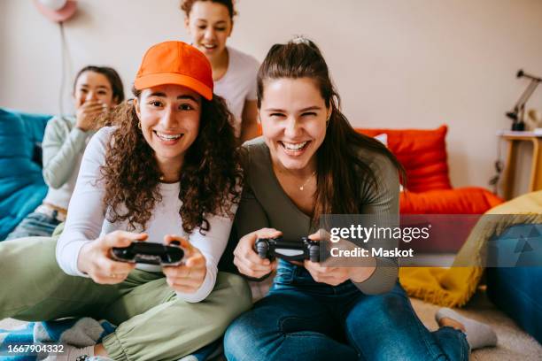 young female friends enjoying video game at home - videospel stockfoto's en -beelden