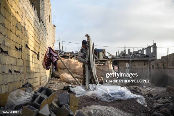 An earthquake survivor folds a blanket in the mountain village of Moulay Brahim in the central province of Al-Haouz, on September 15, 2023. The...