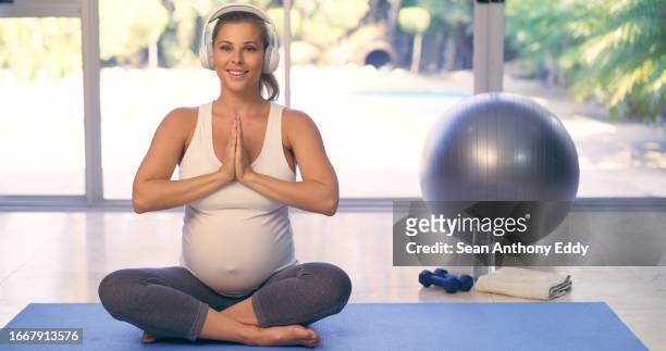 pregnancy, woman and yoga portrait with namaste, zen and meditation with headphones in home studio. lotus position, female pregnant person and relax with peace and breathing with music and balance - lotuspositie stockfoto's en -beelden