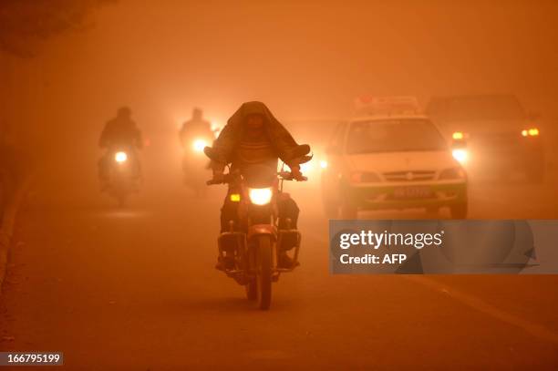 This picture taken on April 16, 2013 shows motorists driving with their lights during a heavy sandstorm in Yecheng county, northwest China's Xinjiang...