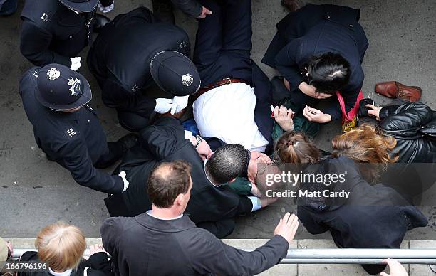 Police come to the aid of a man who collapsed as crowds gather to watch as a Gun Carriage of The King's Troop Royal Horse Artillery carries the...