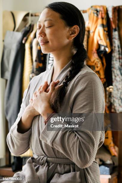 young woman with hands on chest meditating at home - woman flat chest 個照片及圖片檔