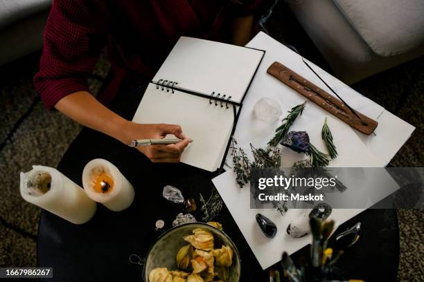midsection of woman writing in book by herbs and crystals on table - incense stock pictures, royalty-free photos & images