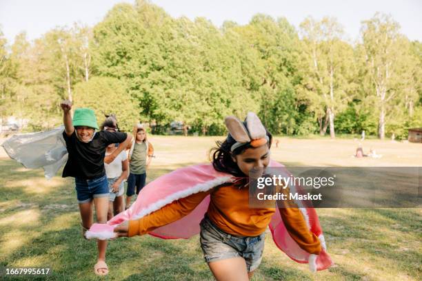 girl wearing rabbit headband running with friends while playing at summer camp - rabbit costume stock pictures, royalty-free photos & images