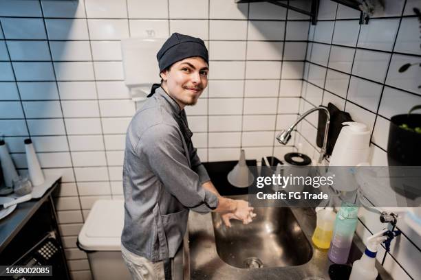 portrait of a chef young man roasting meat on a commercial kitchen - rubbing hands together stock pictures, royalty-free photos & images