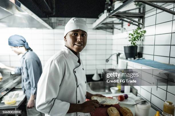 portrait of a chef young man making a sandwich on a commercial kitchen - bolivianischer abstammung stock-fotos und bilder