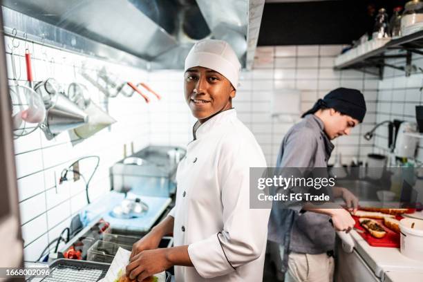 portrait of a chef young man making a sandwich on a commercial kitchen - catering stockfoto's en -beelden