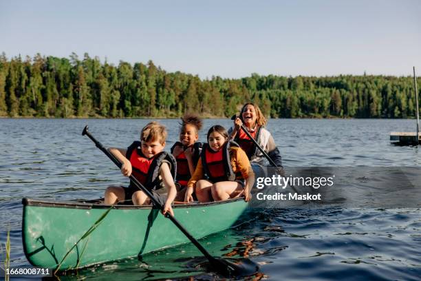 counselor and kids kayaking on lake against sky at summer camp - sommercamp stock-fotos und bilder