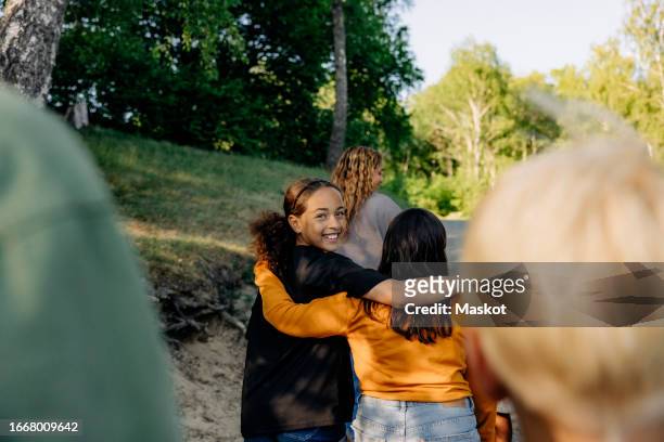 portrait of smiling girl walking with arm around female friend at summer camp - junior high age stock pictures, royalty-free photos & images