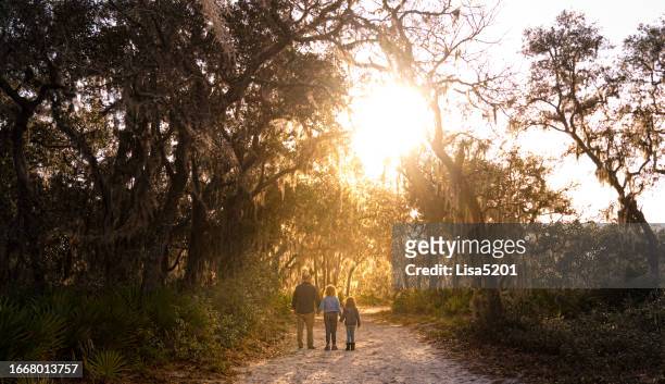 old nature area south central florida, family on a walk outdoors with old oak trees, sunflare and lush spanish moss - central florida v south florida stockfoto's en -beelden