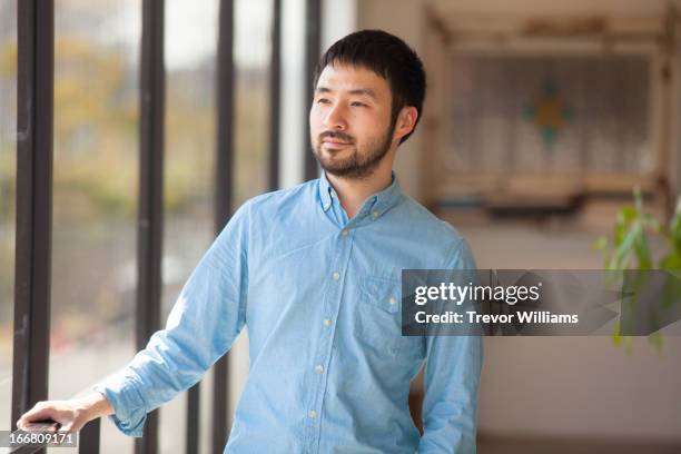 a young man in his 30's standing at a window - seulement des japonais photos et images de collection