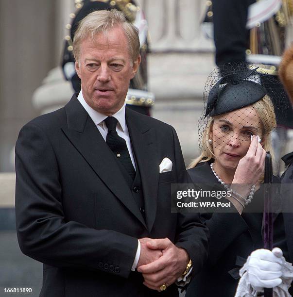 Sarah Thatcher wipes a tear from her eye as she stands next to her husband Mark Thatcher whilst they watch the coffin of former British Prime...