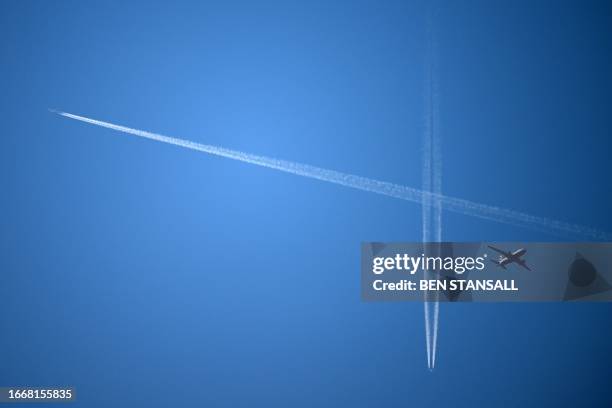 British Airways passenger aircraft flies beneath other aeroplanes and the contrails created by them, in the sky above London on September 15, 2023.