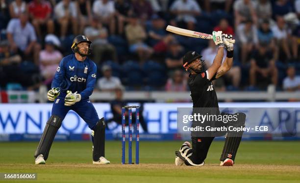 Daryl Mitchell of New Zealand hits out for six runs watched by England wicketkeeper Jos Buttler during the 1st Metro Bank One Day International...