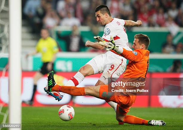 Vedad Ibisevic of Stuttgart and goalkeeper Oliver Baumann of Freiburg compete for the ball during the DFB Cup Semi Final match between VfB Stuttgart...