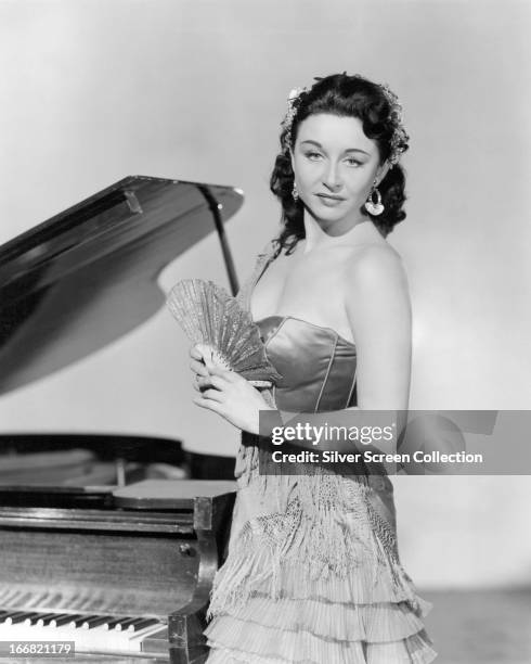 Canadian-born American actress Yvonne De Carlo standing next to a piano, circa 1950.