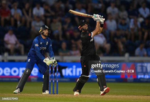 Daryl Mitchell of New Zealand hits out for six runs watched by England wicketkeeper Jos Buttler during the 1st Metro Bank One Day International...