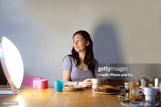 women having breakfast with light therapy lamp - alternative therapy stock pictures, royalty-free photos & images