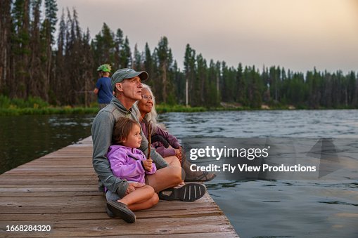 Grandparents and granddaughter enjoy sunset on a lake dock Grandparents and granddaughter enjoy sunset on a lake dock