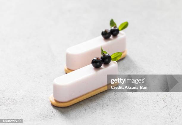black currant cream mousse cakes on cookies, decorated with fresh black currant berries. light grey background. close up - souffle stock pictures, royalty-free photos & images