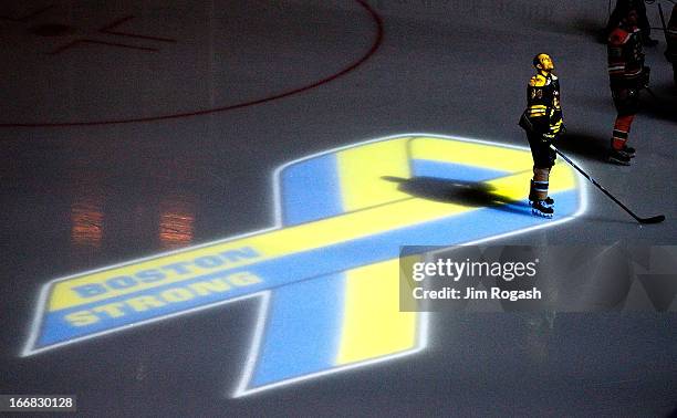 Dennis Seidenberg of the Boston Bruins stands near aa projection of the Boston Marathon Memorial Ribbon seen on the ice during pre game ceremonies in...