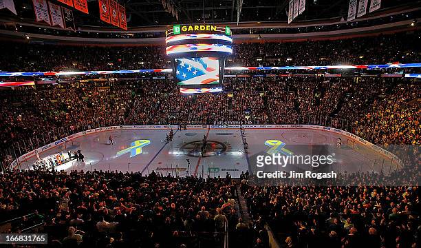 Projections of the Boston Marathon Memorial Ribbon are seen on the ice during pre-game ceremonies in remembrance of the Boston Marathon bombing...