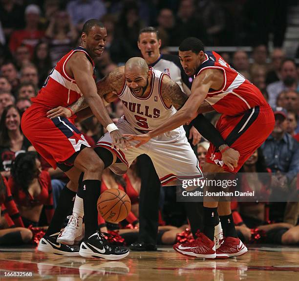 Carlos Boozer of the Chicago Bulls tries to recapture the ball under pressure from Jason Collins and Garrett Temple of the Washington Wizards at the...