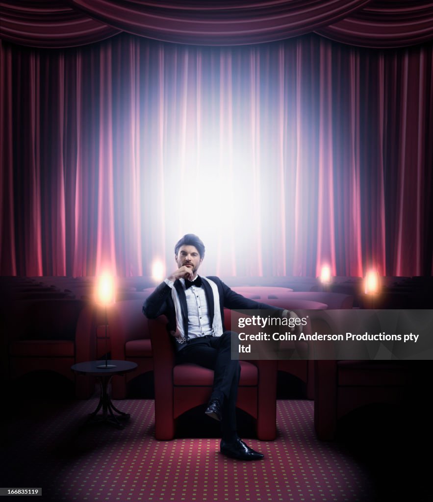 Hispanic man in tuxedo sitting in empty lounge