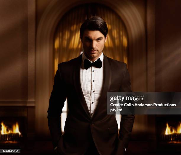 hispanic man in tuxedo standing in living room - tuxedo stock-fotos und bilder