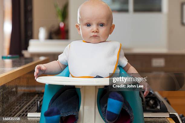 caucasian baby sitting in high chair - bib stock pictures, royalty-free photos & images