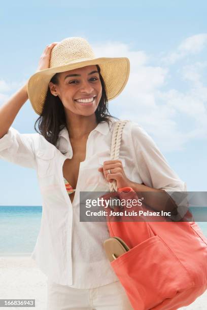 black woman carrying tote bag on beach - beach bag foto e immagini stock