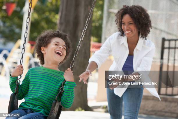 mother pushing son on swing at park - woman on swing stock pictures, royalty-free photos & images